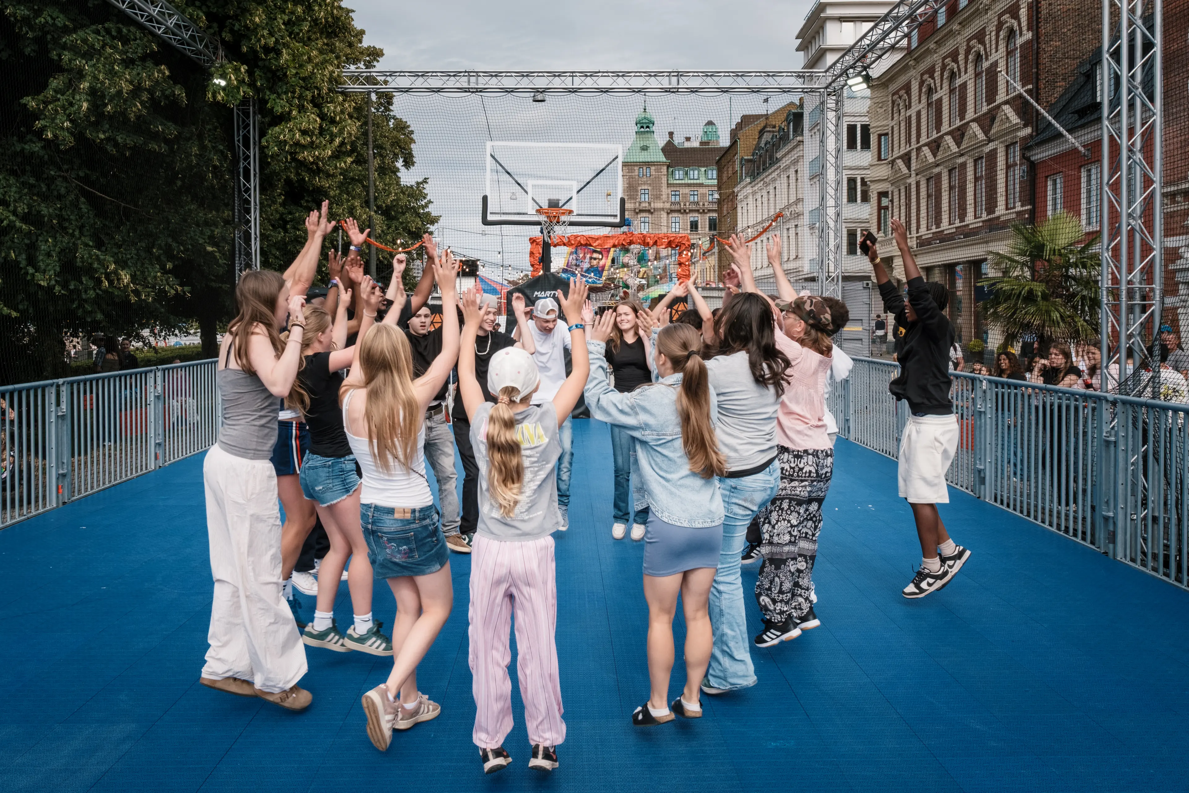 På Ungdomsområdet på Malmöfestivalen står många ungdomar i en ring med händerna upp i luften.
